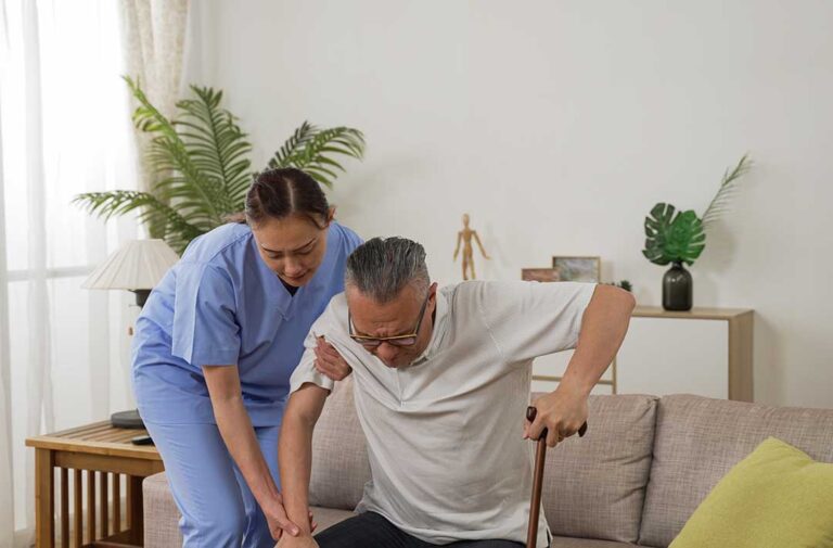 A middle-aged caregiver interviews with a family in a cozy living room, discussing a list of questions over tea.
